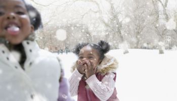 Mixed race girl playing outdoors in falling snow