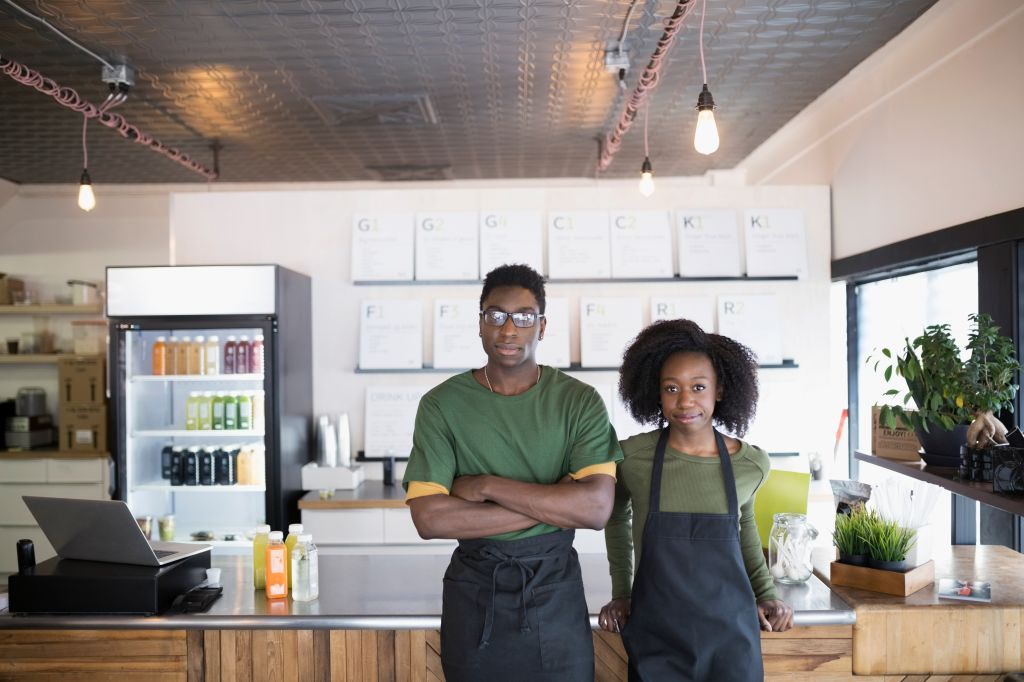 Portrait confident young man and woman working at juice bar
