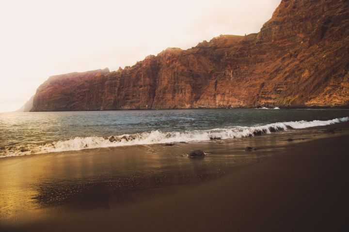 Stunning landscape of the Los Gigantes cliffs with the beach during sunset light with vibrants colors during travel vacations in Tenerife island.