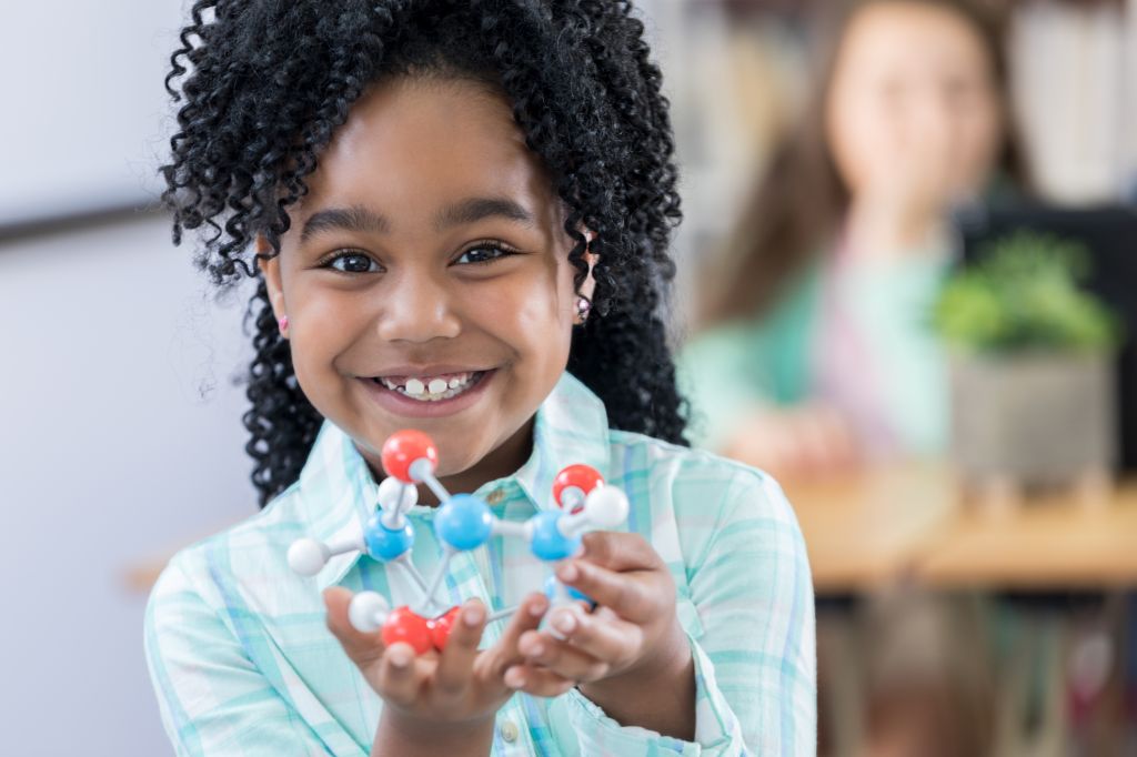 Adorable elementary student showing molecular structure model