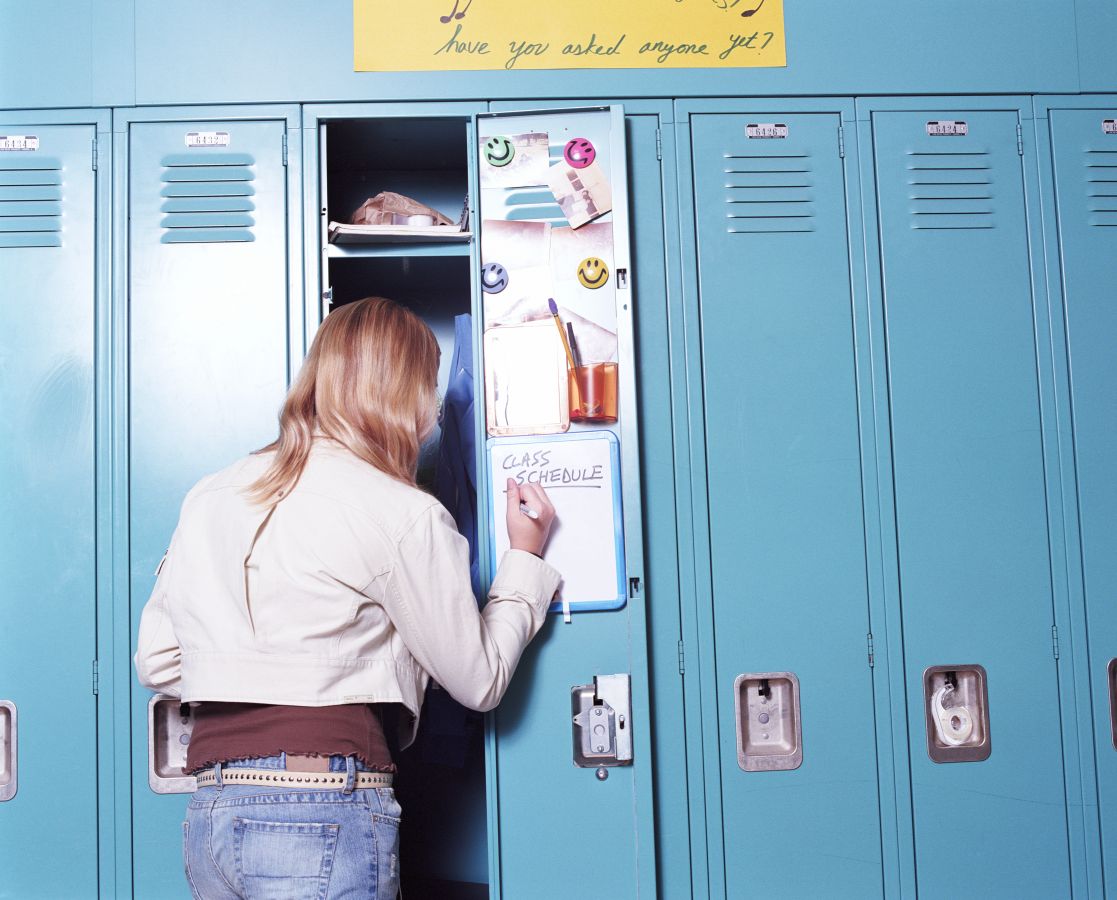 Teenage girl (13-15) writing class schedule on whiteboard, rear view