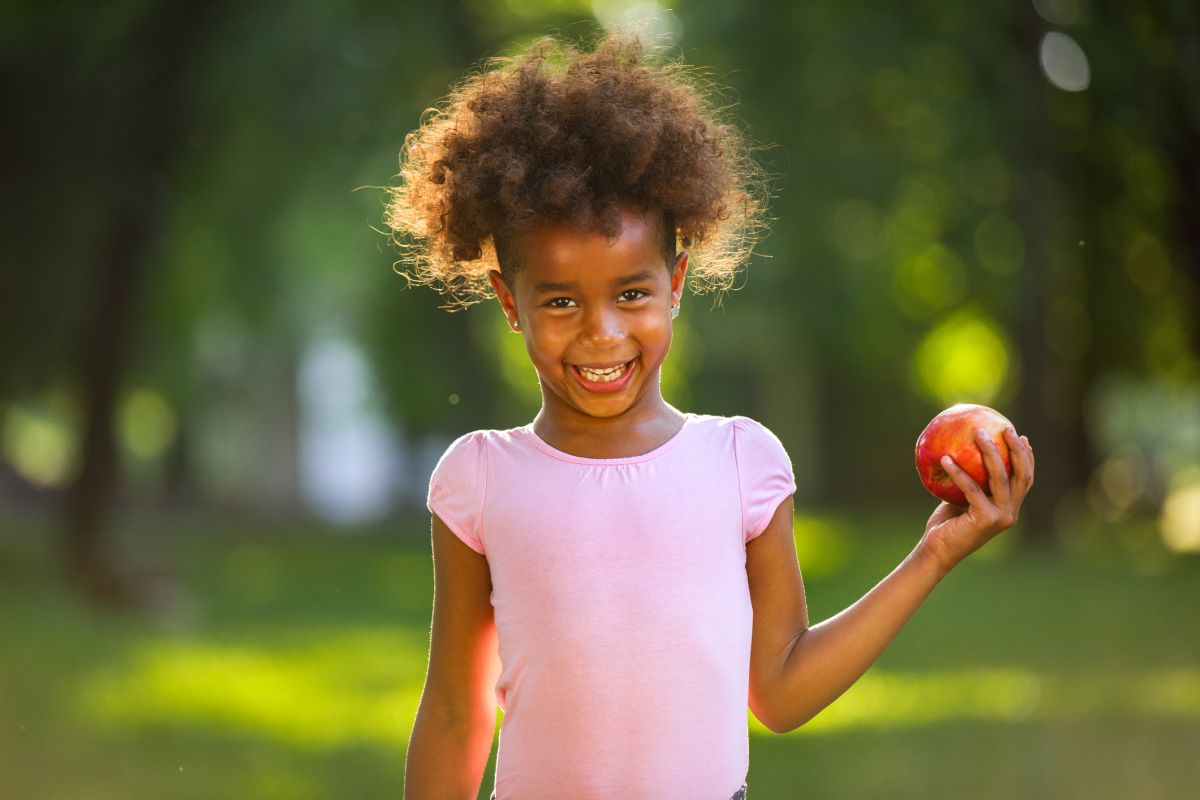 Adorable girl with red apple smiling at the camera