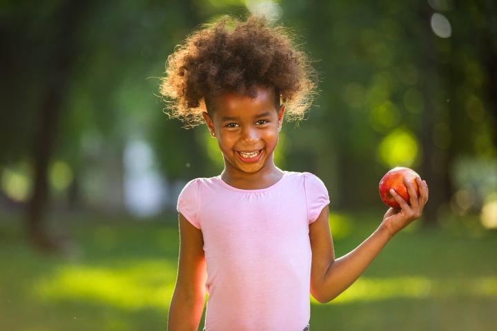 Adorable girl with red apple smiling at the camera