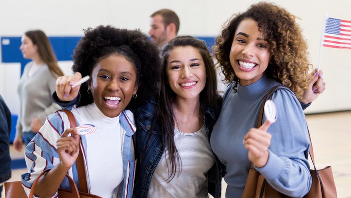 Three young women with big smiles right after voting