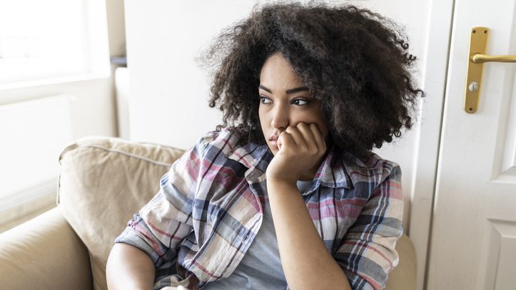 Pensive young woman using smart phone at home