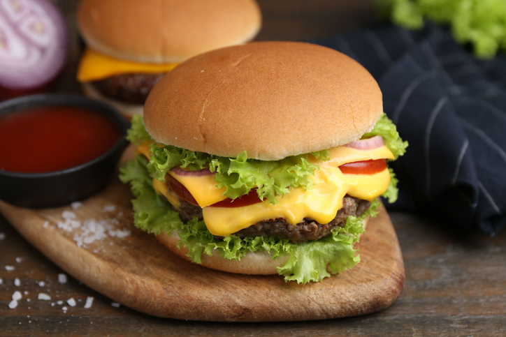 Tasty cheeseburgers served on wooden table, closeup