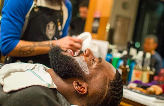 A person with a beard receiving a haircut in a barbershop setting.