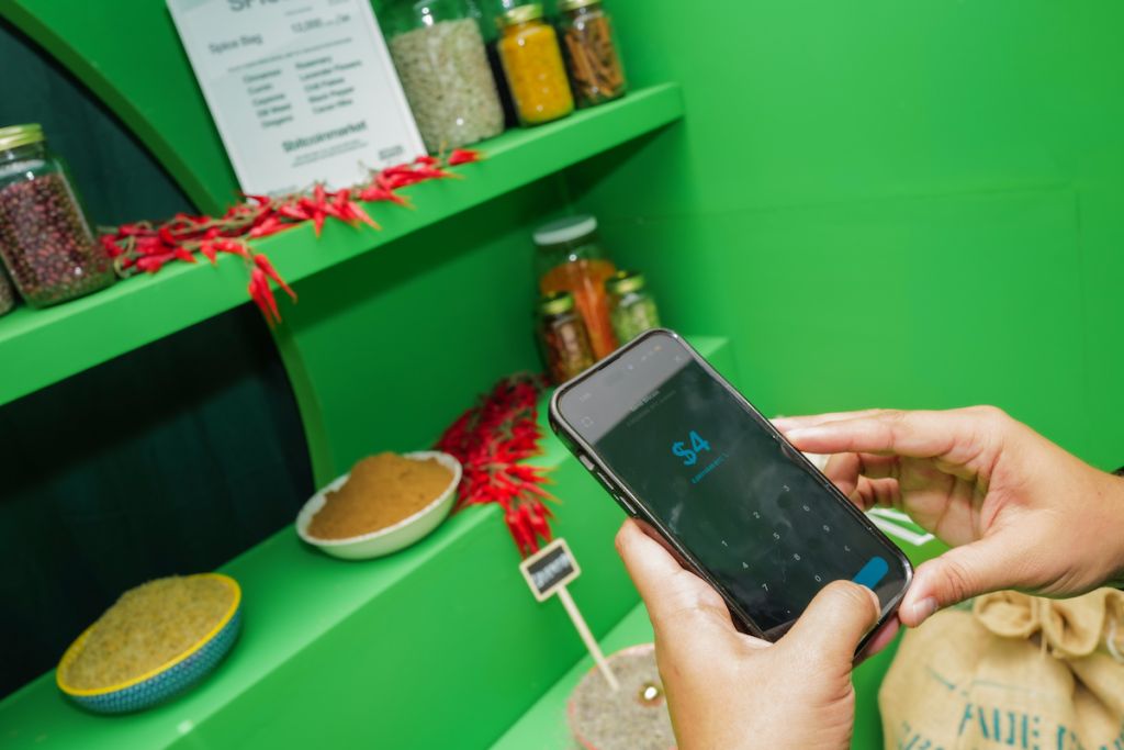A person's hands holding a smartphone displaying the number "54" against a green background with various spice jars and cooking utensils.