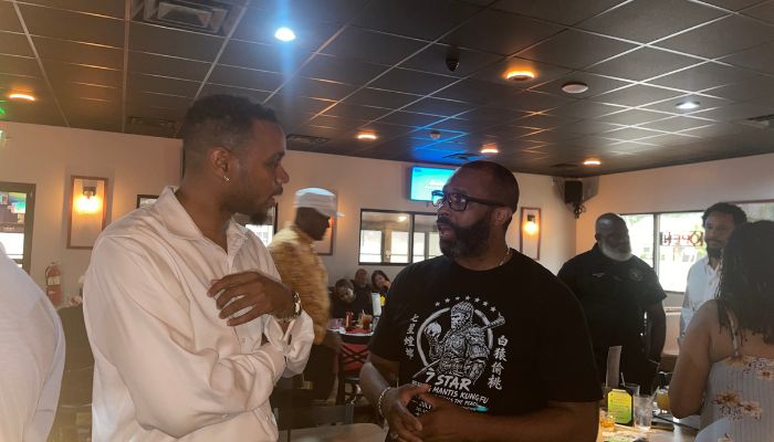 Two men in casual clothing engaged in conversation in a restaurant or bar setting.