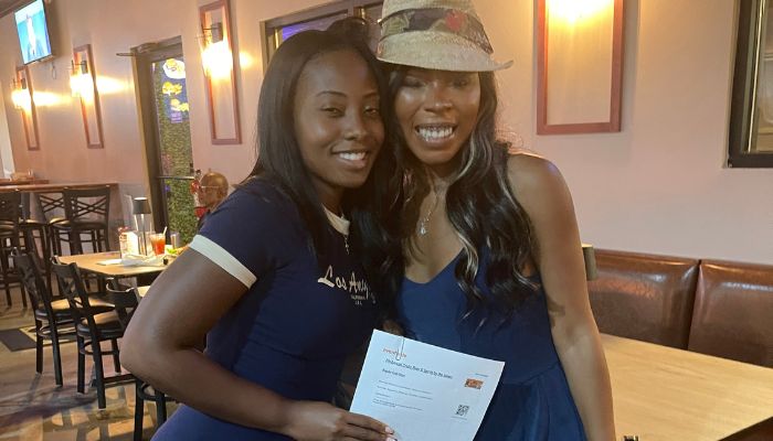 Two smiling young women posing together in a restaurant setting.