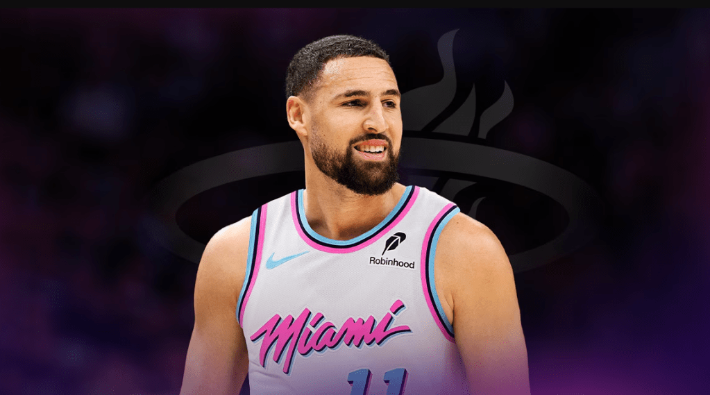 A basketball player wearing a Miami jersey with the number 11 and the Robinhood logo, smiling on a basketball court.